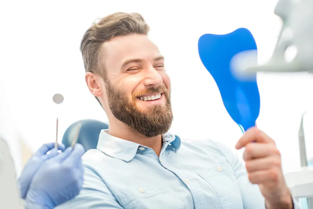 man looking at his beautiful smile sitting at the dental office