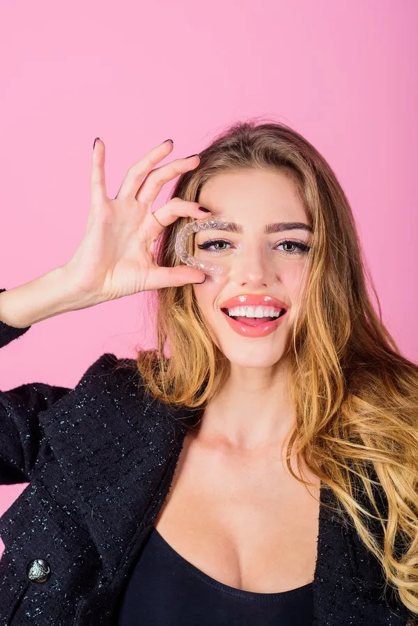 Woman posing against pink background.