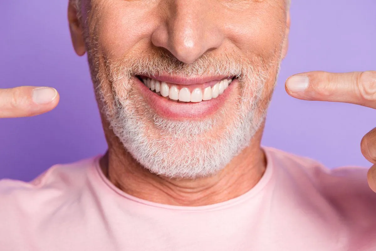 Smiling old man pointing his teeth