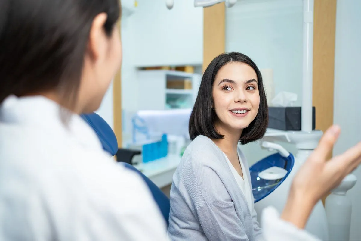 Asian dentist giving advice to patient girl about oral care treatment.