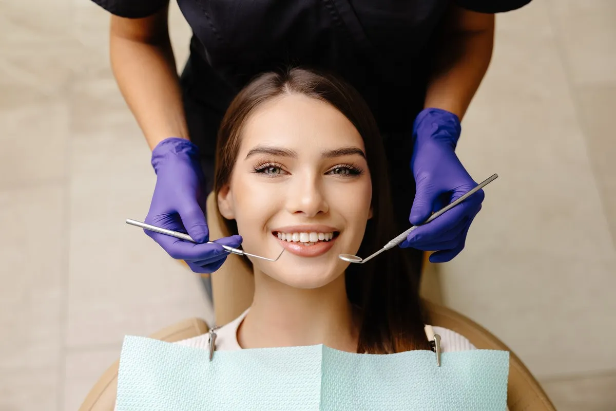 Happy patient during a visit to the dentist. The doctor is checking teeth using a dental instrument, ensuring proper oral care in the dentistry clinic
